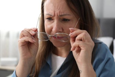 Evde gözlük takan görme sorunu olan bir kadın.