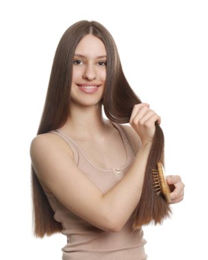 Smiling teenage girl brushing her shiny hair on white background