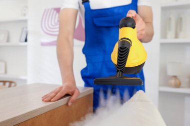 Temizlikçi yastığı evde buhar temizleyicisiyle temizliyor.