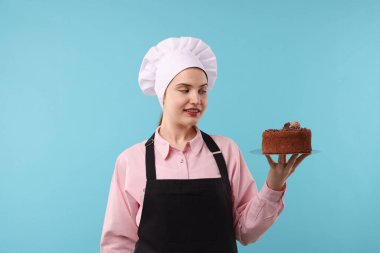 Açık mavi arka planda lezzetli çikolatalı pasta yapan bir pastacı.