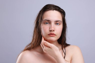 Gri arka planda doğal ten rengi olan kadın portresi, yakın plan.