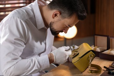 Kapalı mekânda deri çanta değerlendirmesi yapan bir eksper.