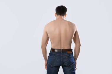 Kotlu bir adam açık gri arka planda poz veriyor.