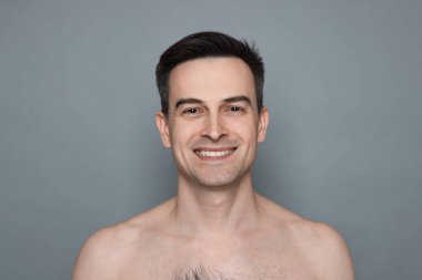 Gri arka planda tıraş olduktan sonra gülümseyen adam