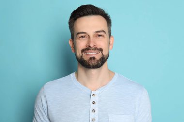 Açık mavi arka planda tıraş olmadan önce gülümseyen adam