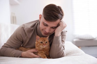 Evdeki kanepede sevimli kızıl kedili adam.