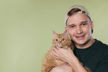 Açık yeşil arka planda sevimli kızıl kedili adam, metin için boşluk