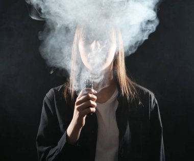 Siyah arkaplanda elektronik sigara içen kadın