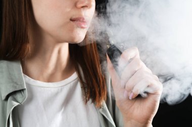 Siyah arkaplanda elektronik sigara içen kadın, yakın plan