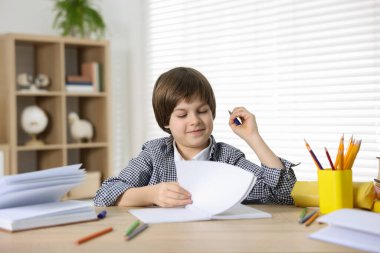 Evde, masada ödev yapan sevimli küçük çocuk.
