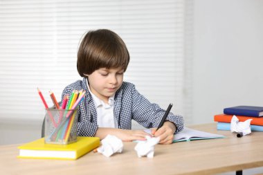 Evde, masada ödev yapan sevimli küçük çocuk.