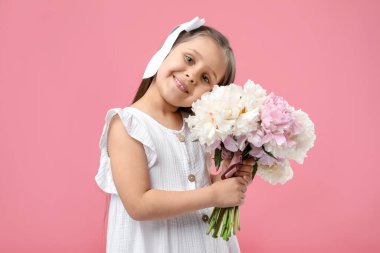 Pembe arka planda bir buket güzel şakayığı olan tatlı küçük bir kız.