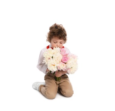 Beyaz arka planda bir buket güzel şakayığı olan sevimli küçük bir çocuk.