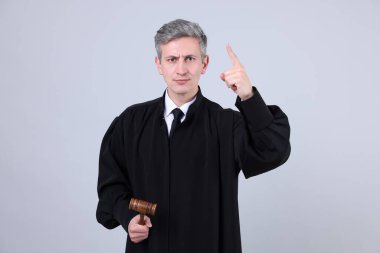 Gri arka planda parmak sallayan çekiçli yargıç