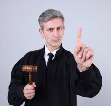 Gri arka planda parmak sallayan çekiçli yargıç