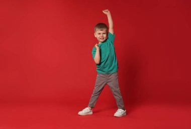 Kırmızı arka planda dans eden küçük mutlu çocuk, mesaj için boşluk