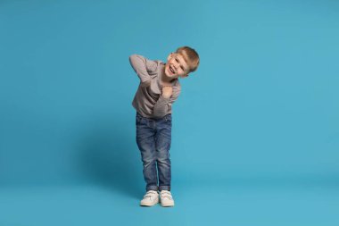 Mutlu küçük çocuk açık mavi arka planda dans ediyor