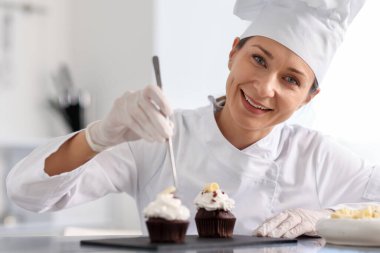 Cımbızlı şekerlemeci mutfakta kek süslüyor.