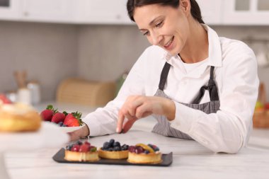 Sofrada yaban mersinli tart süsleyen şekerci.