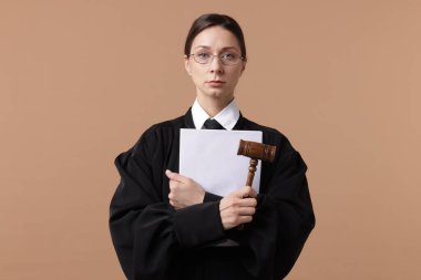 Açık kahverengi arkaplanlı çekiç ve belgelerle hakim