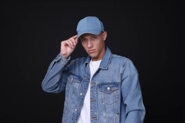 Siyah arka planda şık kot şapkalı genç adam.