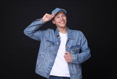 Siyah arka planda şık kot şapkalı genç adam.