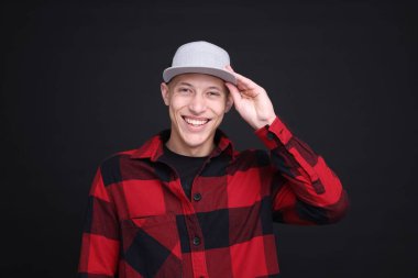 Siyah arka planda şık bir beyzbol şapkası giyen genç adam.