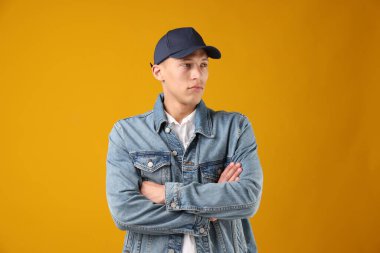 Turuncu arka planda şık beyzbol şapkalı genç adam.