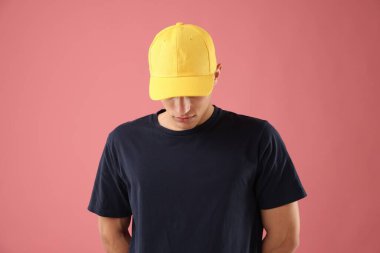 Pembe arka planda şık bir beyzbol şapkası takan genç adam.