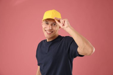 Pembe arka planda şık bir beyzbol şapkası takan genç adam.