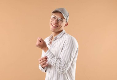 Beyzbol şapkalı genç adam bej arka planda.