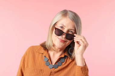 Pembe arka planda şık giyinmiş son sınıf öğrencisi bir kadın.