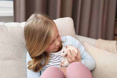 Evdeki kanepede tatlı beyaz fareli küçük kız.