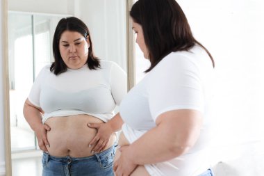 İçeride aynanın yanında göbeği aşırı yağlı bir kadın var. Aşırı kilolu