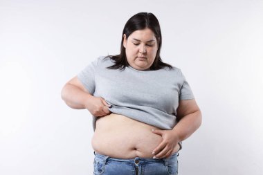 Beyaz arka planda aşırı göbek yağı olan bir kadın.
