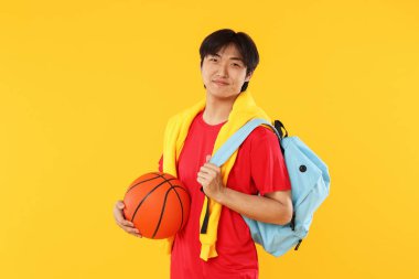 Basketbol ve turuncu arka planda sırt çantası olan öğrenci.