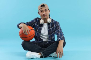 Kulaklıklı öğrenci ve açık mavi arka planda basketbol topu.