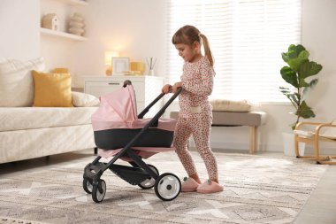 Evinde oyuncak bebek arabası olan sevimli küçük bir kız.