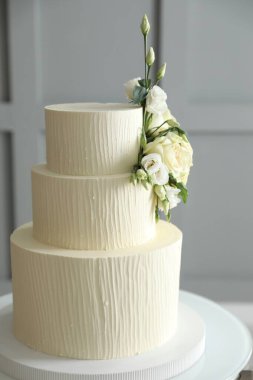 İçerideki masada çiçeklerle süslenmiş nefis düğün pastası.