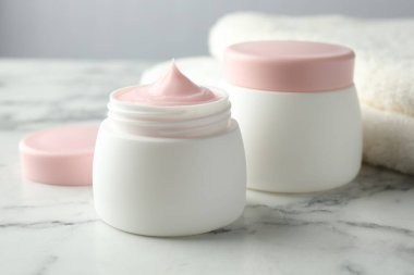 Beyaz mermer masanın üzerinde bir kavanoz nemlendirici vücut kremi, yakın plan.