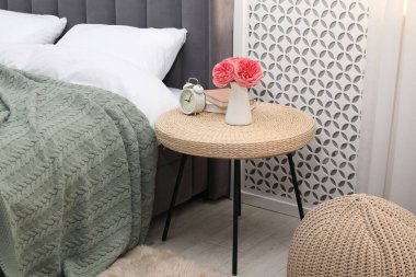 Çalar saati, kitapları ve yatağın yanında dekorasyonu olan yan masa.