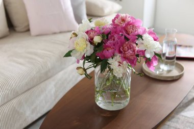 Bir buket güzel şakayık ve sehpanın üzerinde su. Kapalı alanda mesaj için yakın çekim. İç tasarım