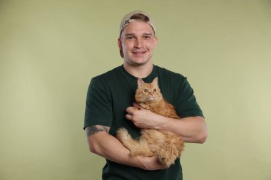 Açık yeşil arka planda sevimli kızıl kedisi olan adam.