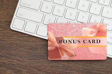 Şık tasarımı olan bonus kart ve tahta masa üzerinde bilgisayar klavyesi, üst görünüm