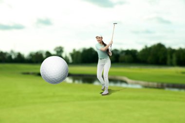 Golfçü, golf sopası ile topa vuruyor.