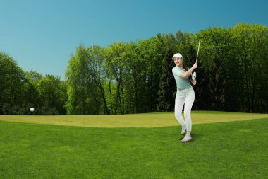 Yeşil sahada golf oynayan bir kadın.
