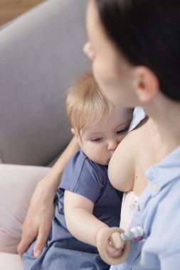 Anne küçük bebeğini evde emziriyor.