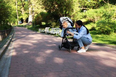 Anne, bebek arabasında sevimli bebeğiyle dışarıda kuşlara bakıyor.