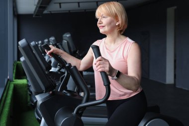 Son sınıf kadın spor salonunda eliptik makine eğitimi alıyor.