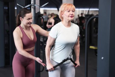 Spor salonunda profesyonel antrenör tarafından yönetilen son sınıf kadın makara makinesi eğitimi.